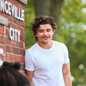 Student leaning against a sign