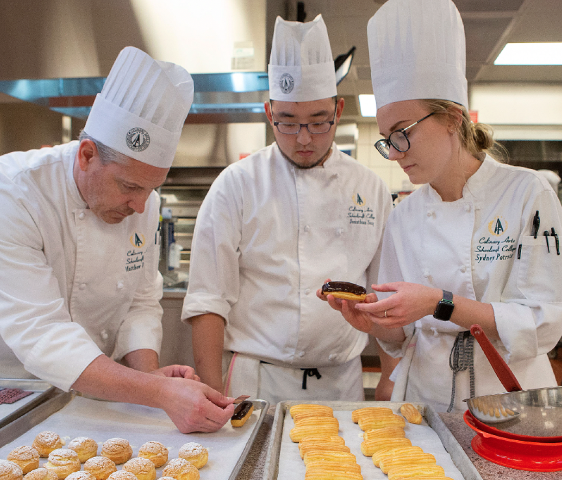 faculty chef helping students with pastry tray setting
