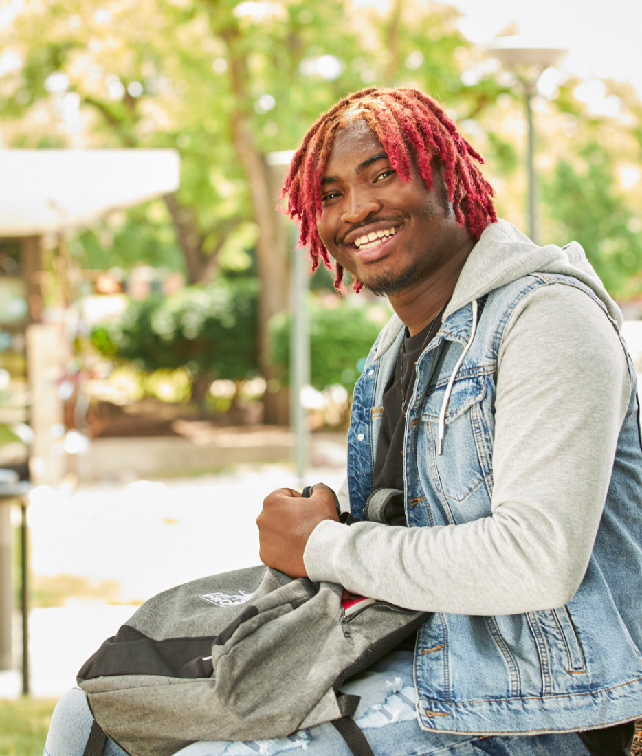 Student smiling holding book bag