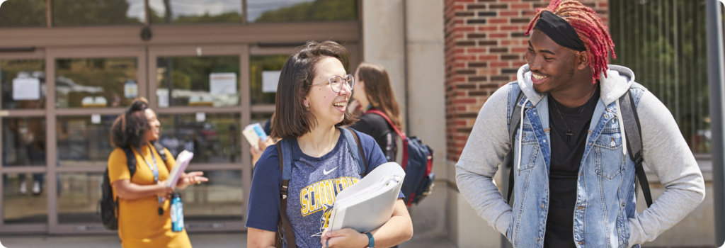 students walking outside carrying books