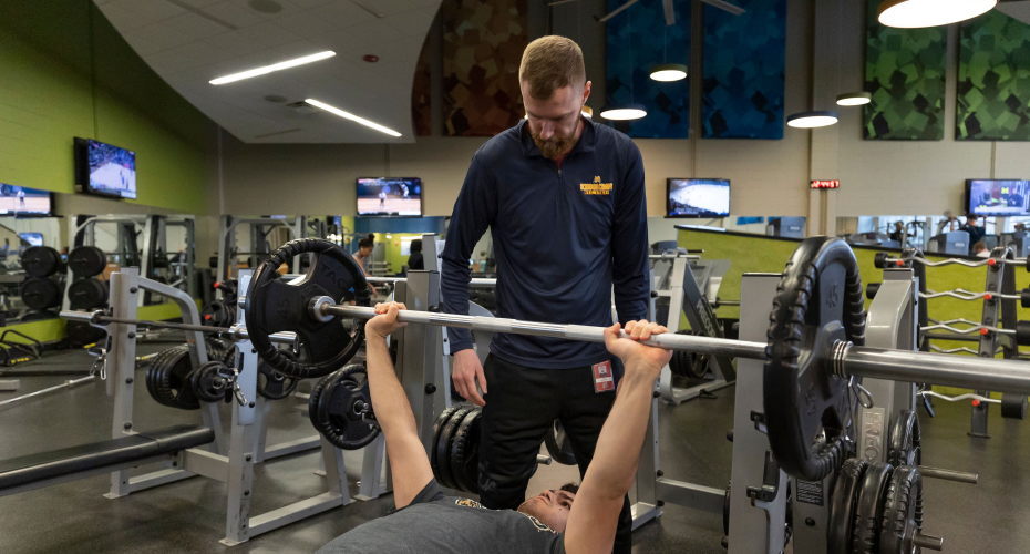 person lifting weights with spotter