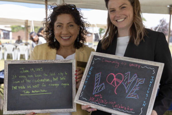 Two people hold small chalkboards that contain positive messages
