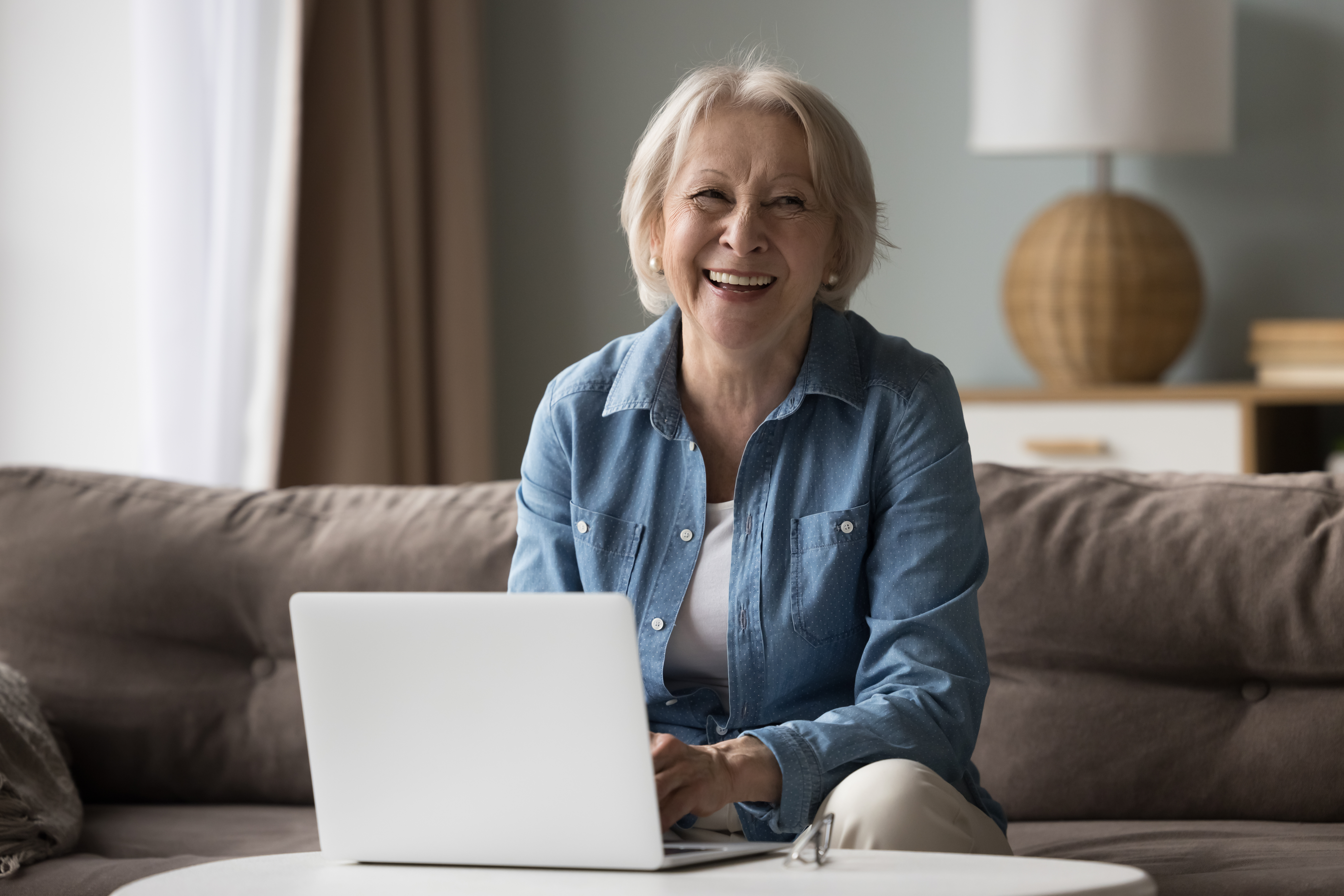Adult sitting on couch with laptop smiling