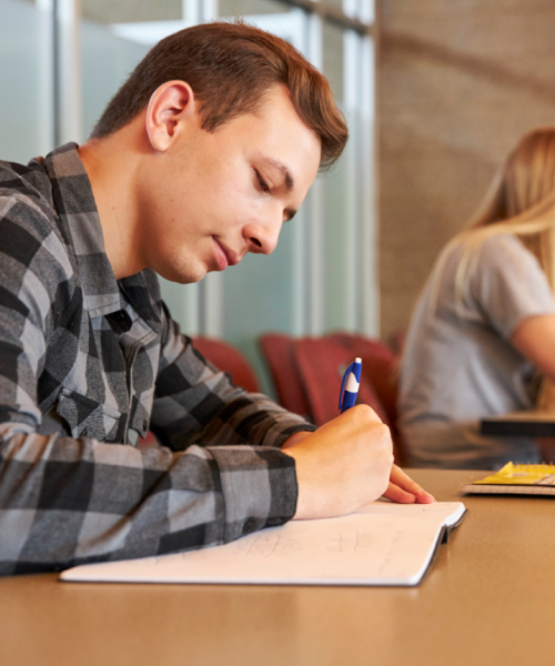 student writing at his desk