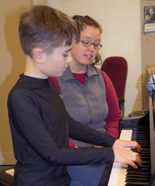 child playing piano with adult