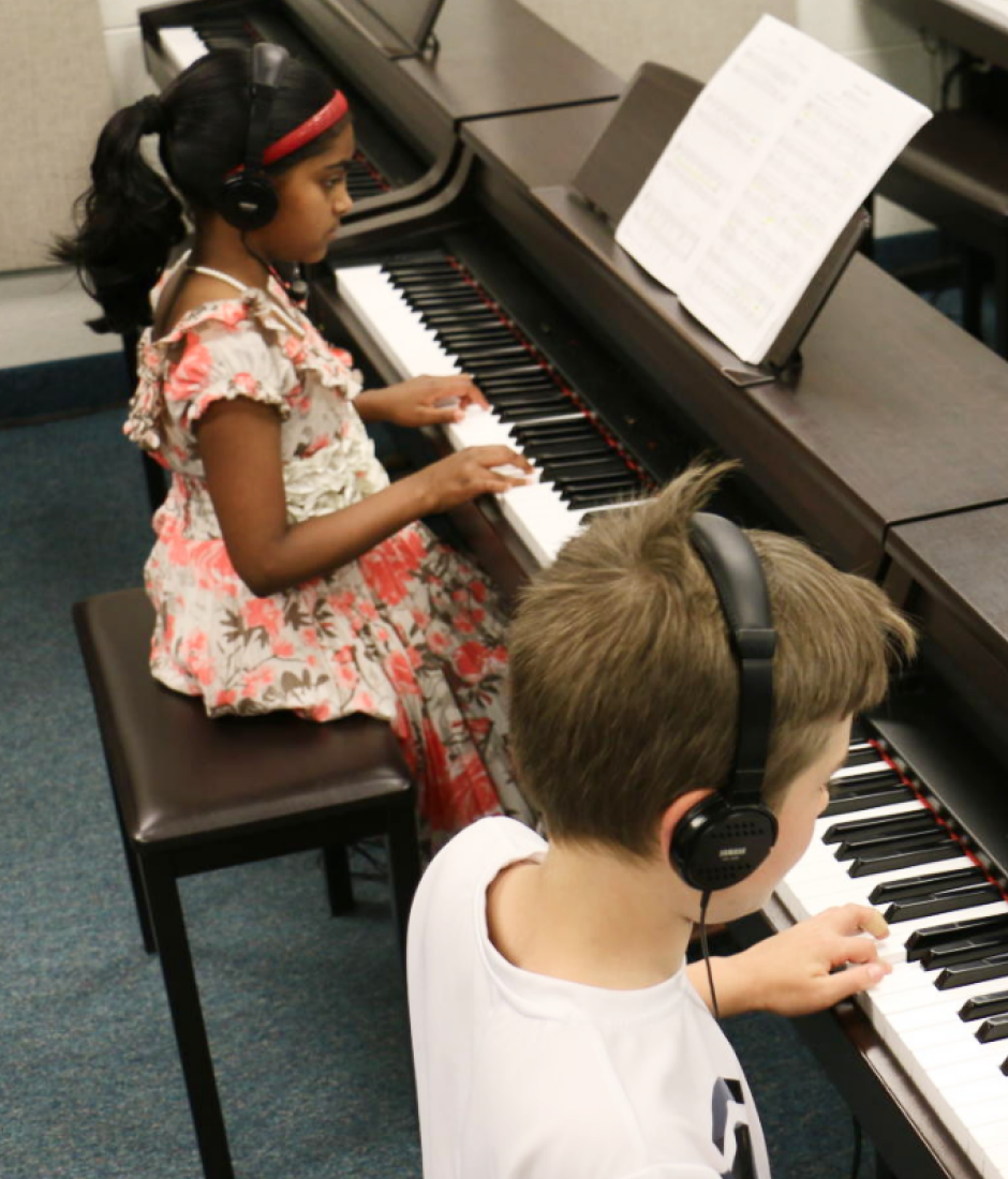 children wearing headphones playing piano