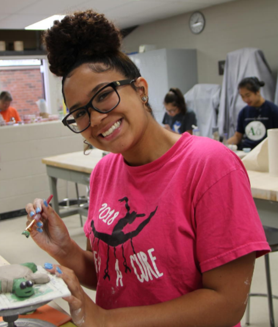 Student painting a clay turtle