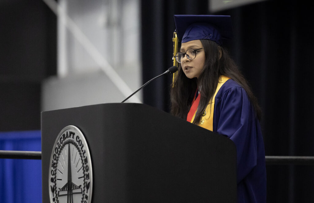 student in regalia speaking at podium