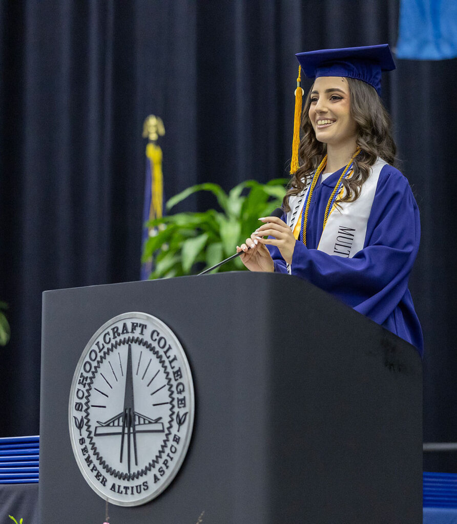 student in regalia speaking at podium