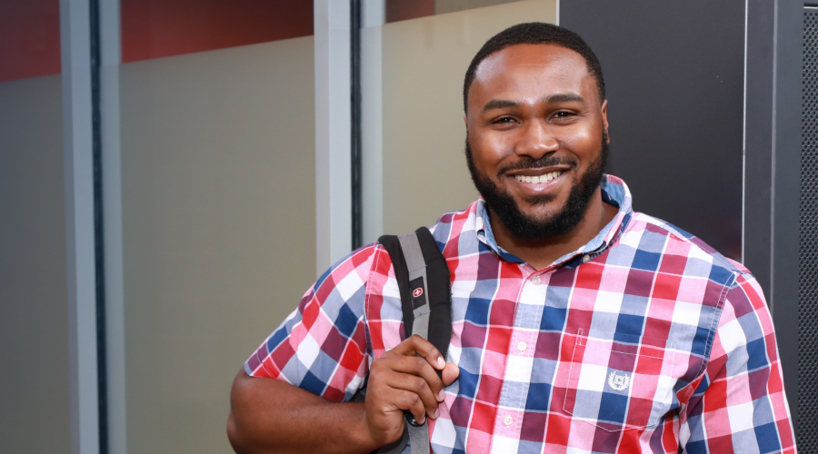 student holding backpack smiling