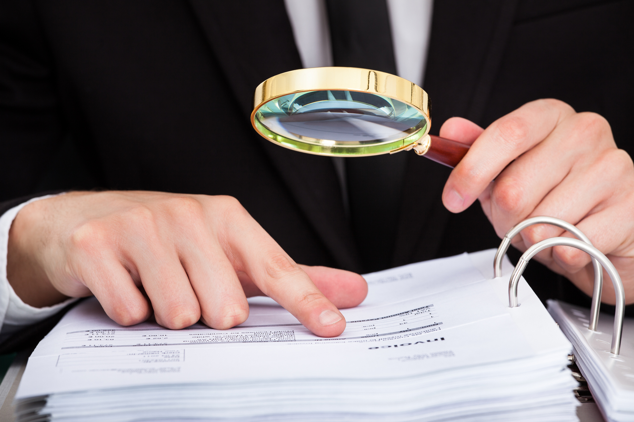 person viewing binder with magnifier glass