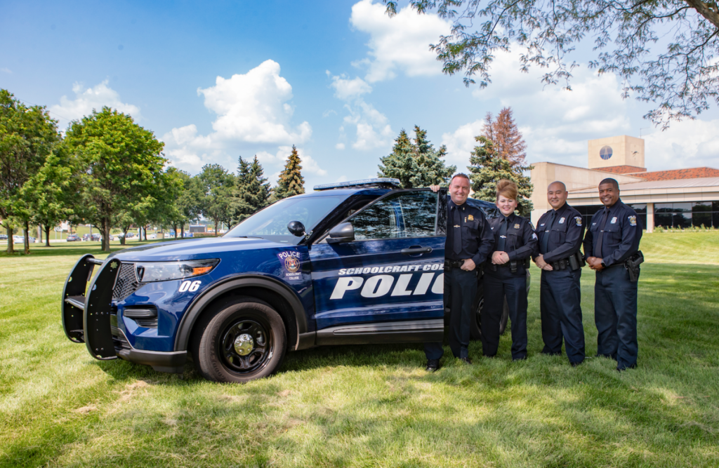 police staff by police car on grass