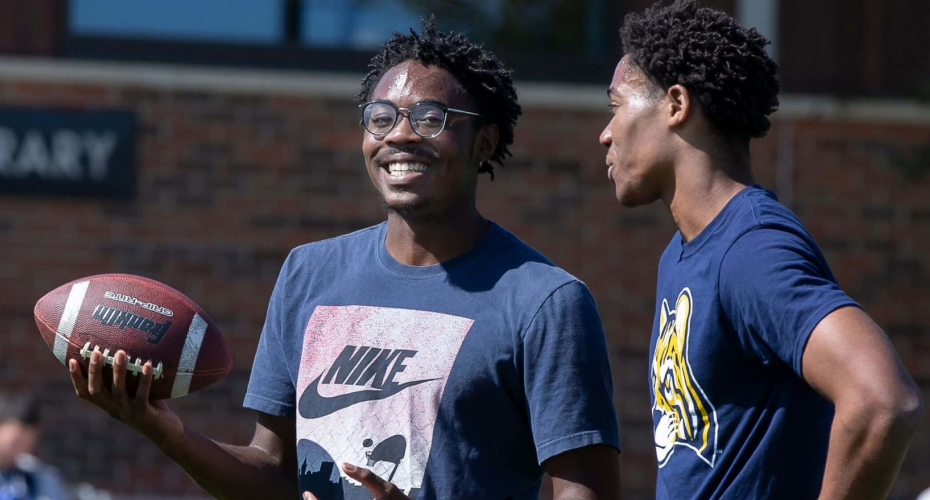 Students handling football outside