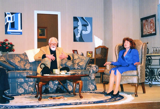 A staged scene of a couple talking in a living room setting.