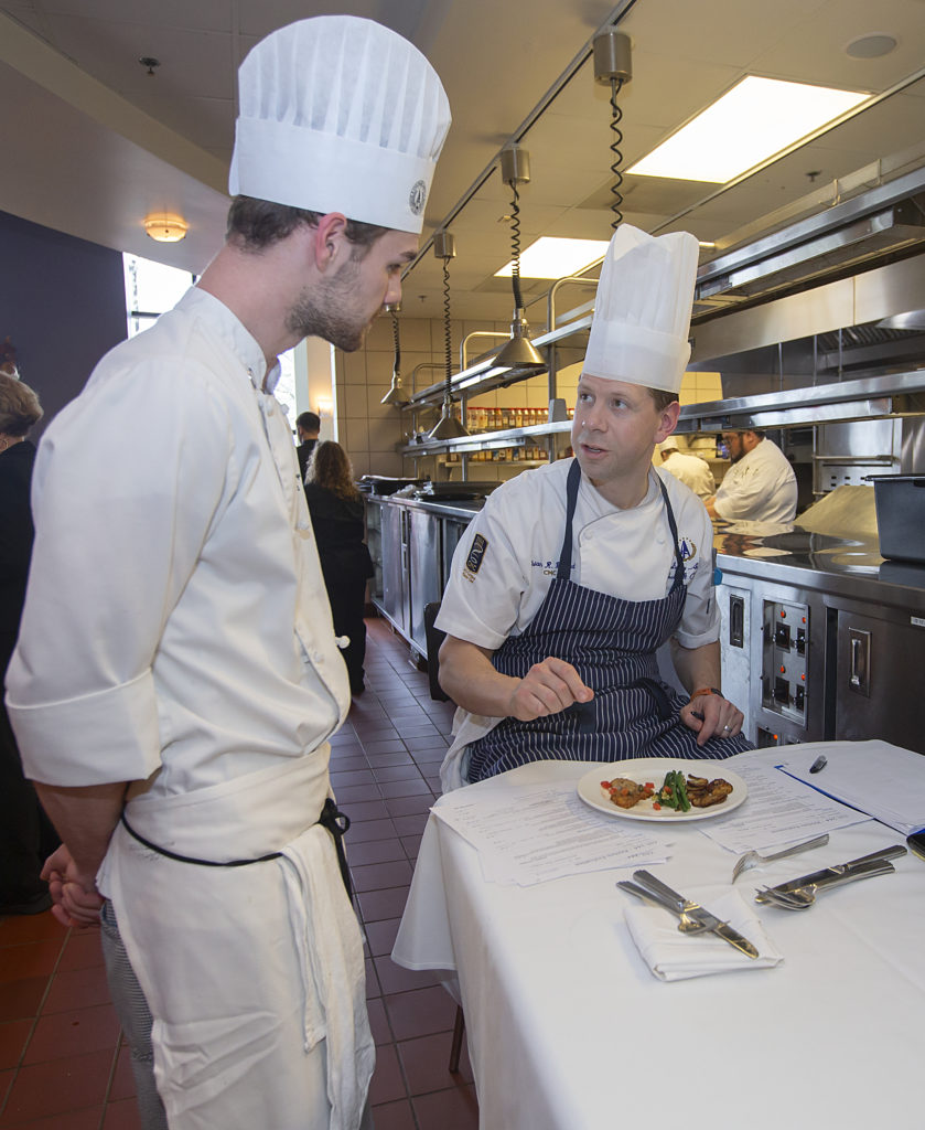 Chef Beland teaching teaching a student in the kitchen