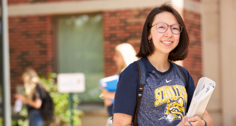 Student holding a binder and smiling