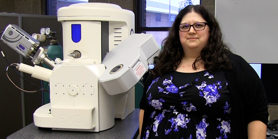 Melissa Gury standing next to a microscope