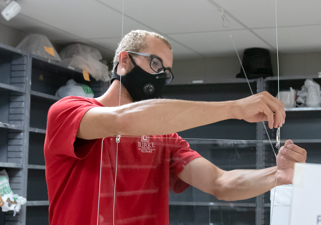 Person attaching wire to plexiglass