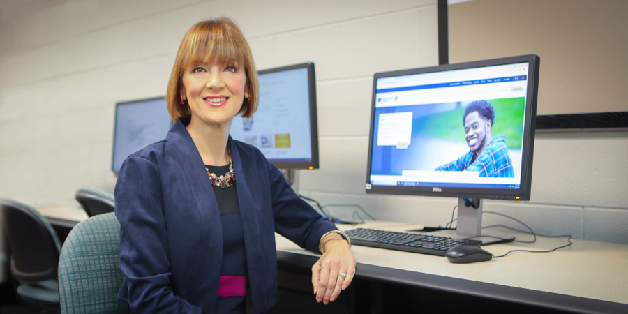 Lori Timmis sitting at a table with a computer behind her