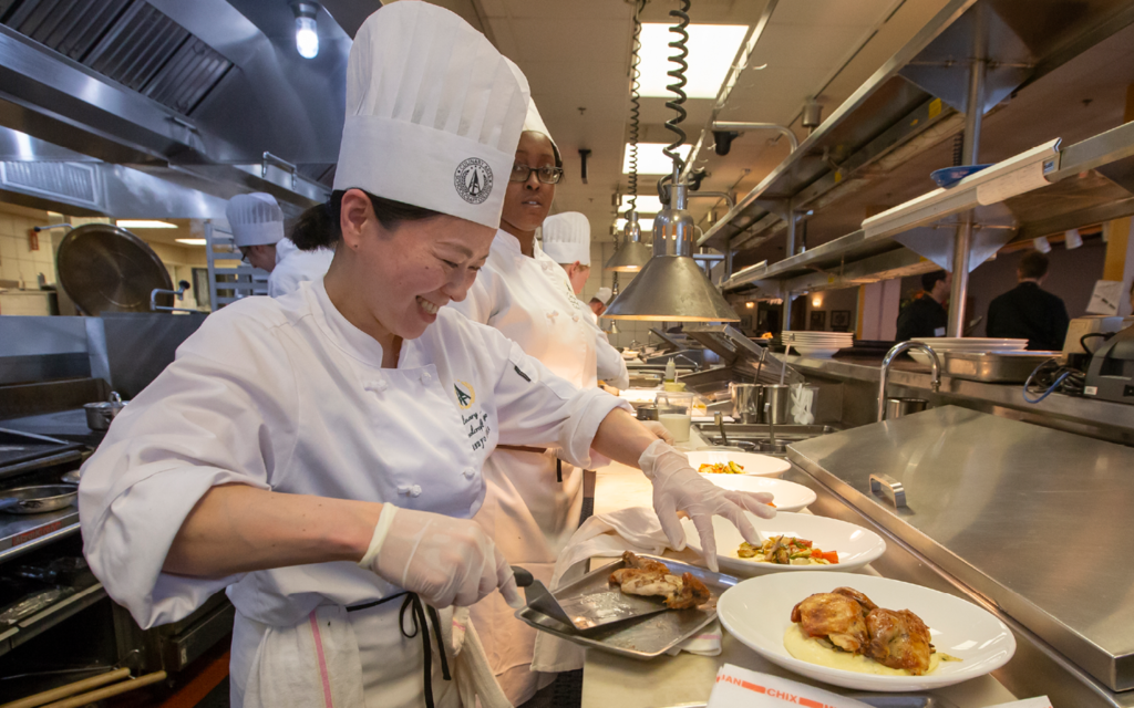 chefs preparing plates in a kitchen