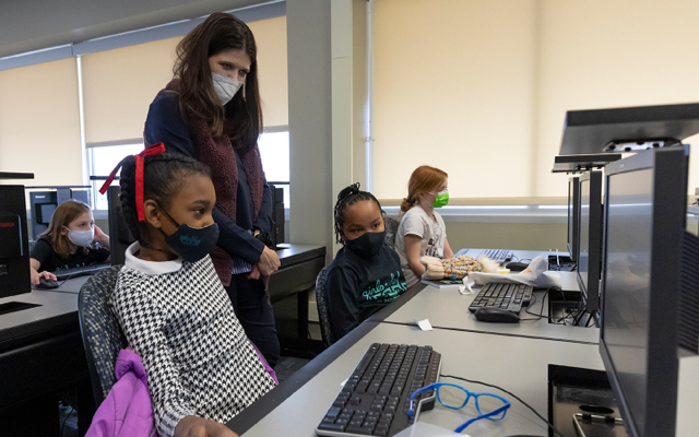 Haley Stevens looking at a computer with children