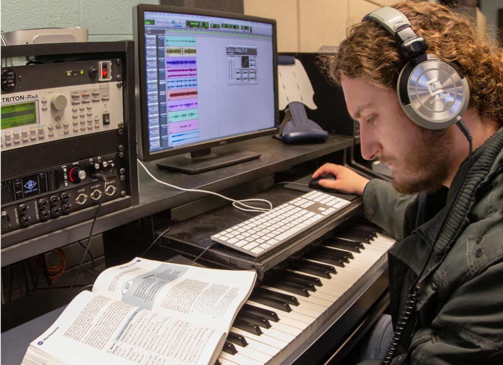 Student with headphones interacting on a computer and piano