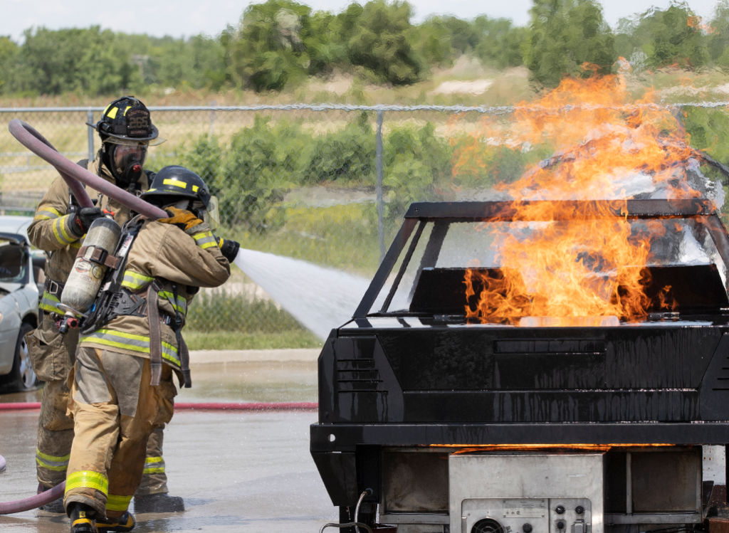 Firefighters watering down a car fire