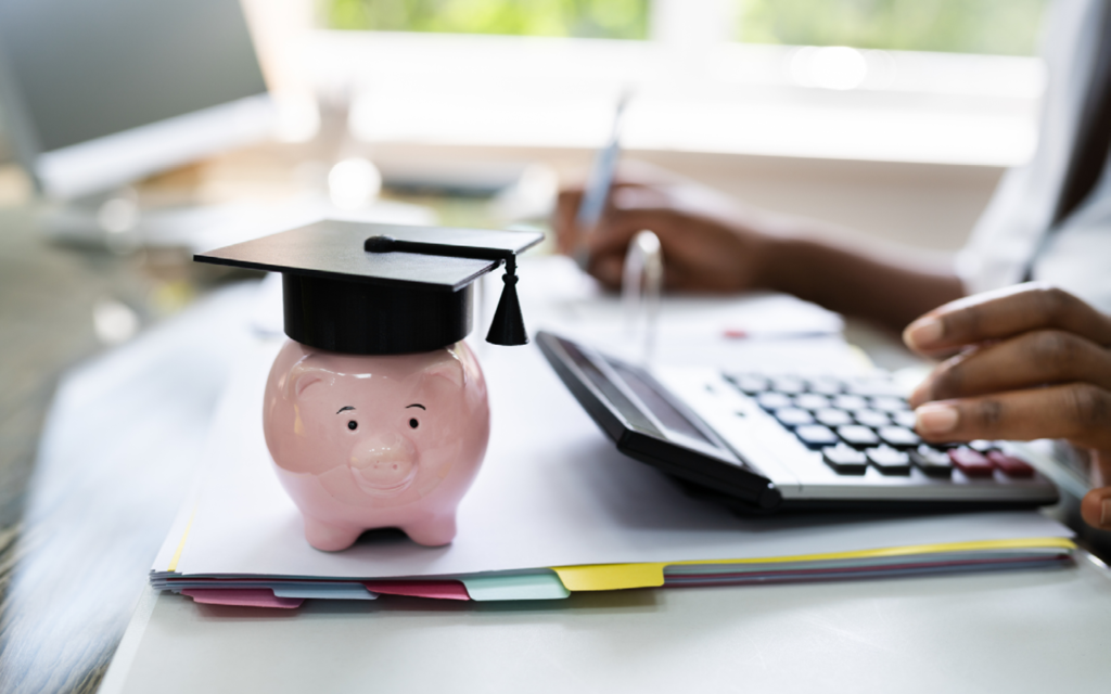 calculator, piggy bank wearing a graduation cap