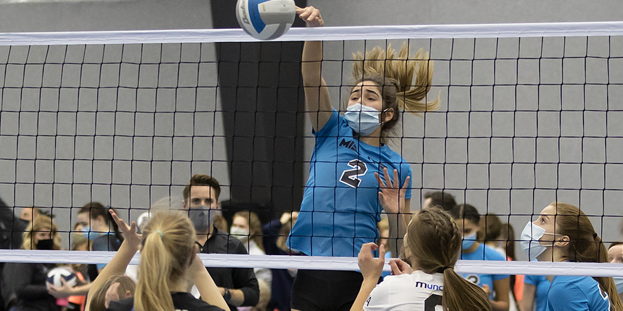 Person spiking a volleyball over the net