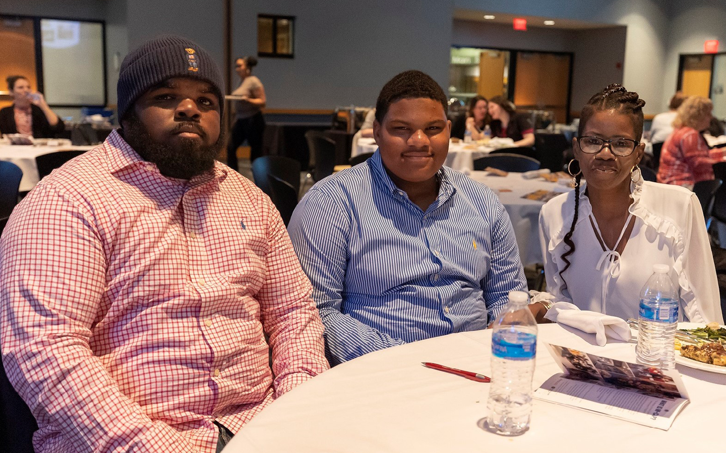 Three attendees smiling around a banquet table