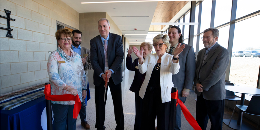 people cutting a ribbon and cheering