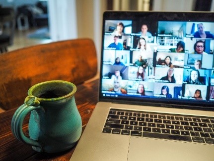 coffee cup next to a laptop with a virtual meeting in progress