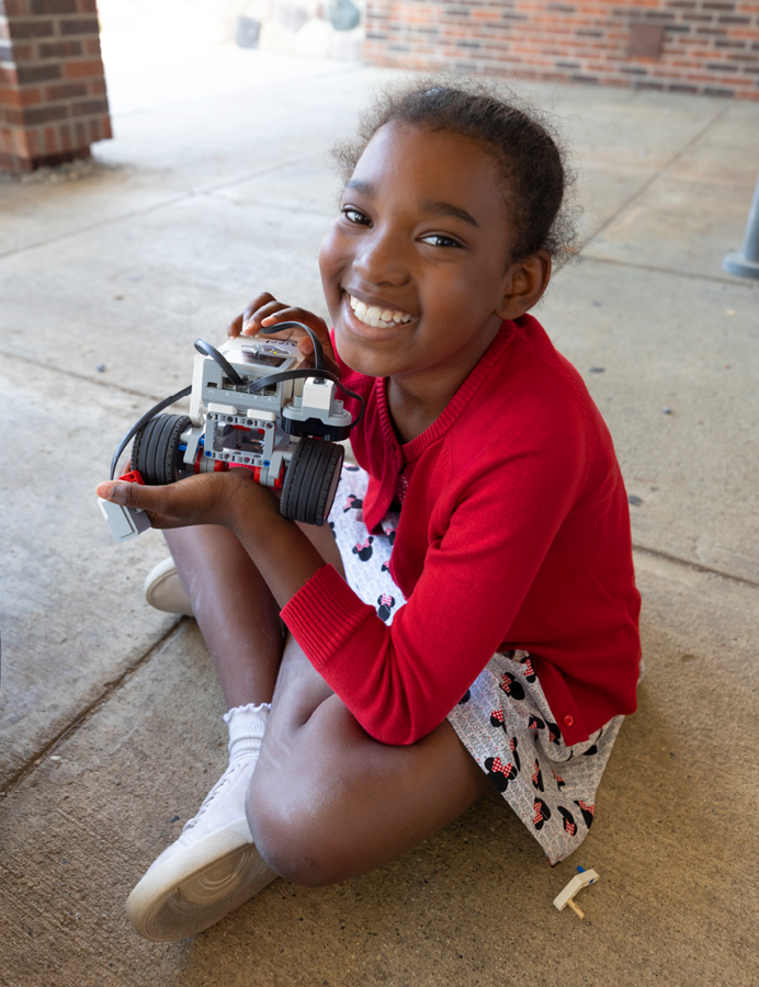 child smiling holding robotic car