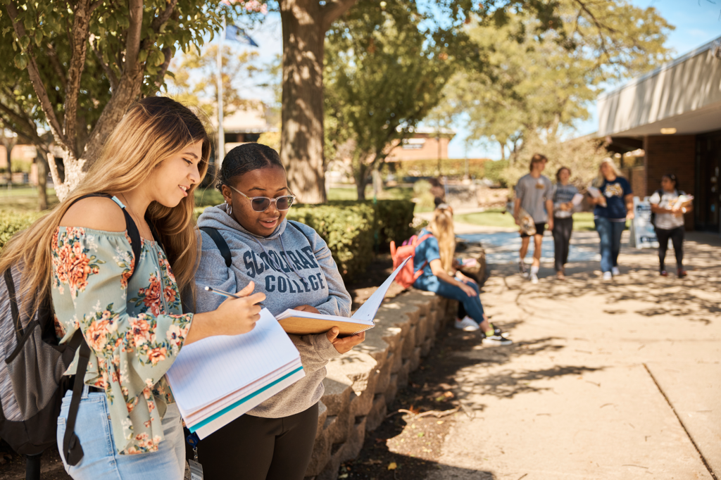 two students reviewing notes together at campus outdoors