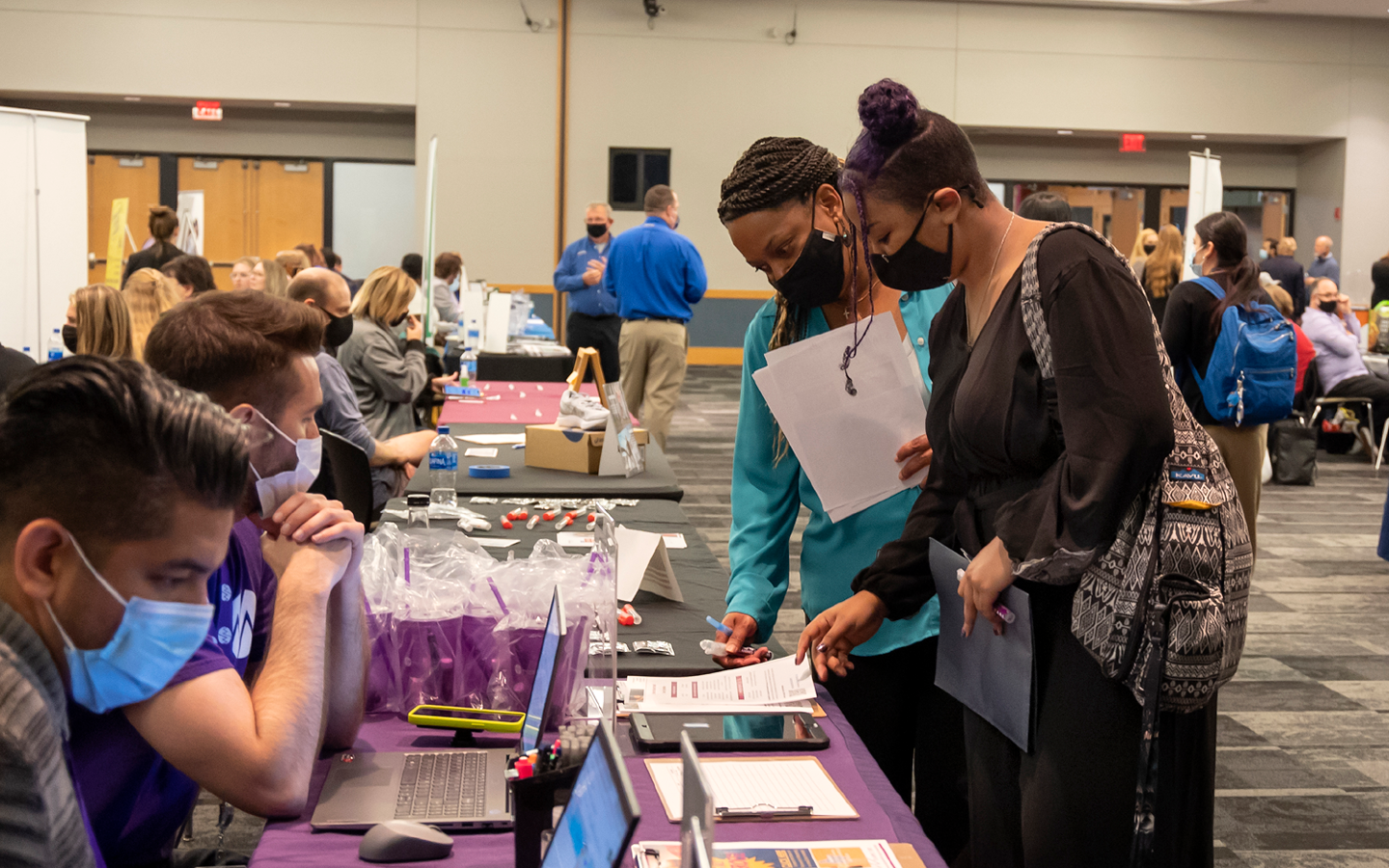 People working tables at the fair present information to attendees