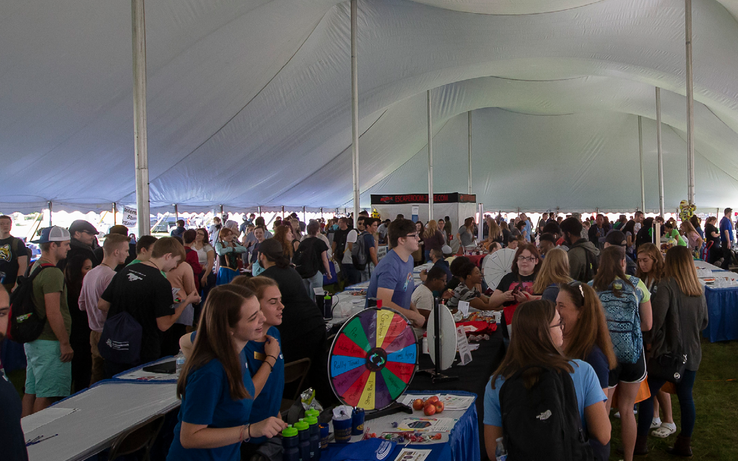 large crowd of tables and attendees under a tent