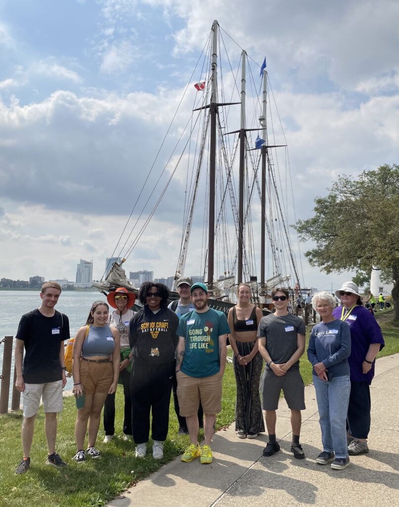 group of students in front of an old wooden ship