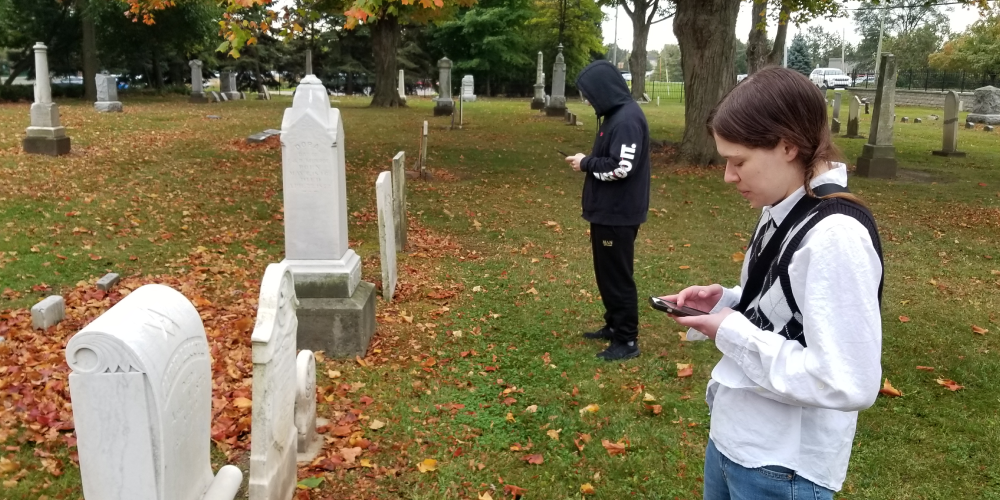 students documenting on their phones at a cemetery