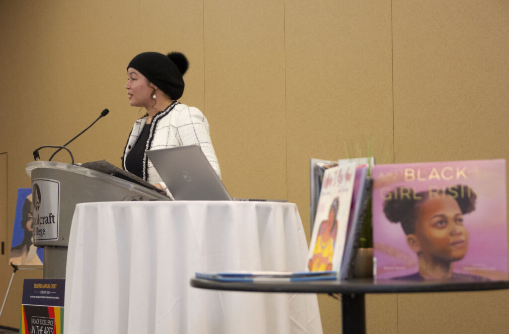 person speaking at podium next to book display