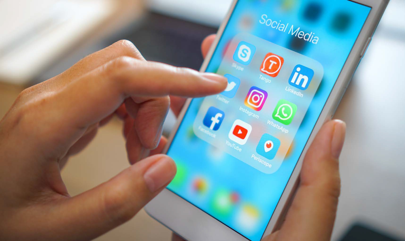A person clicking a social media icon on an iPhone