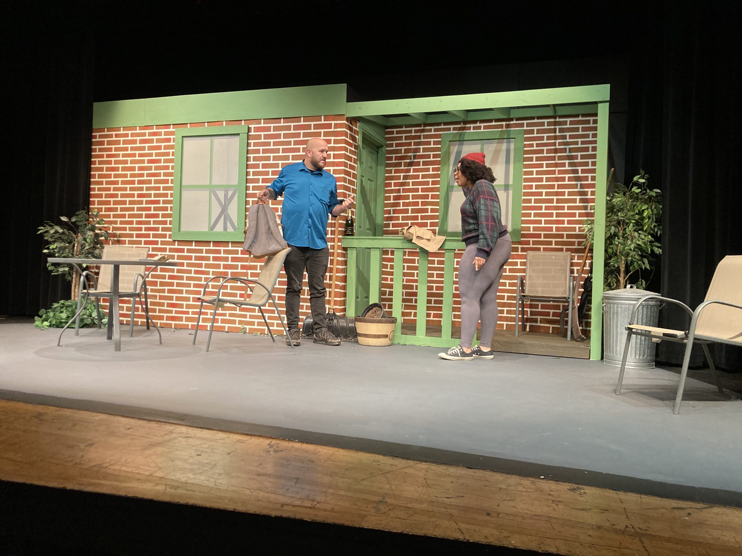 two people talking on a stage set like a brick building