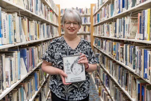 Kristin Keyes holding a book in library