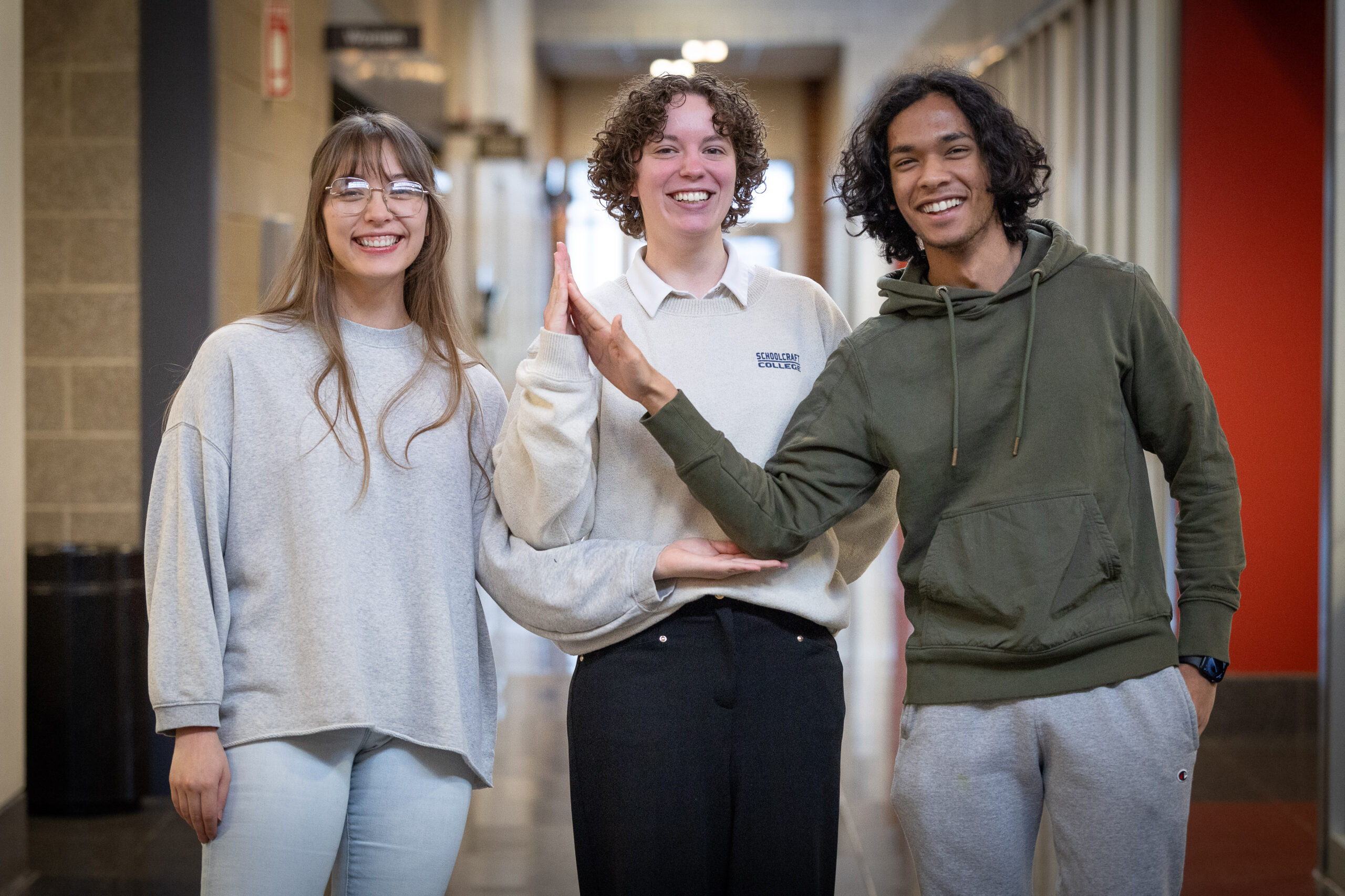 three students creating triangle with their arms