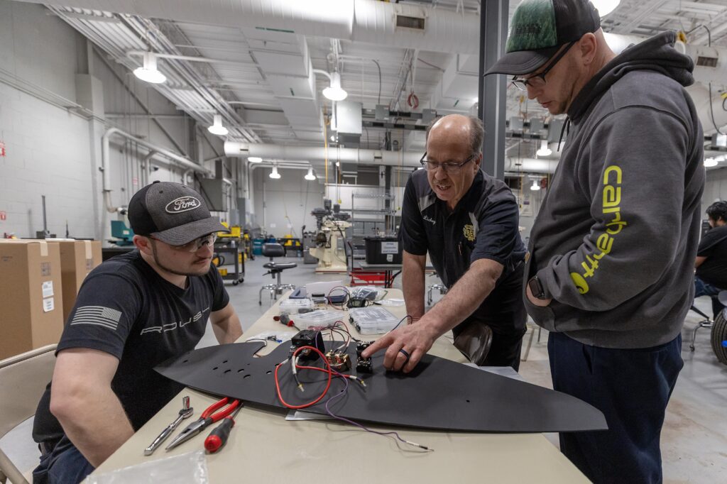 group looking at electrical wiring of a metal part