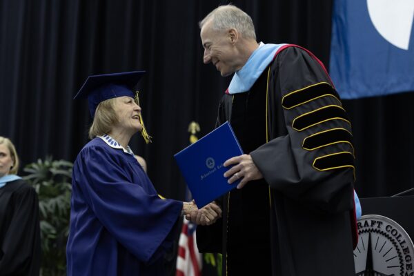 student shaking hands with college president at graduation stage