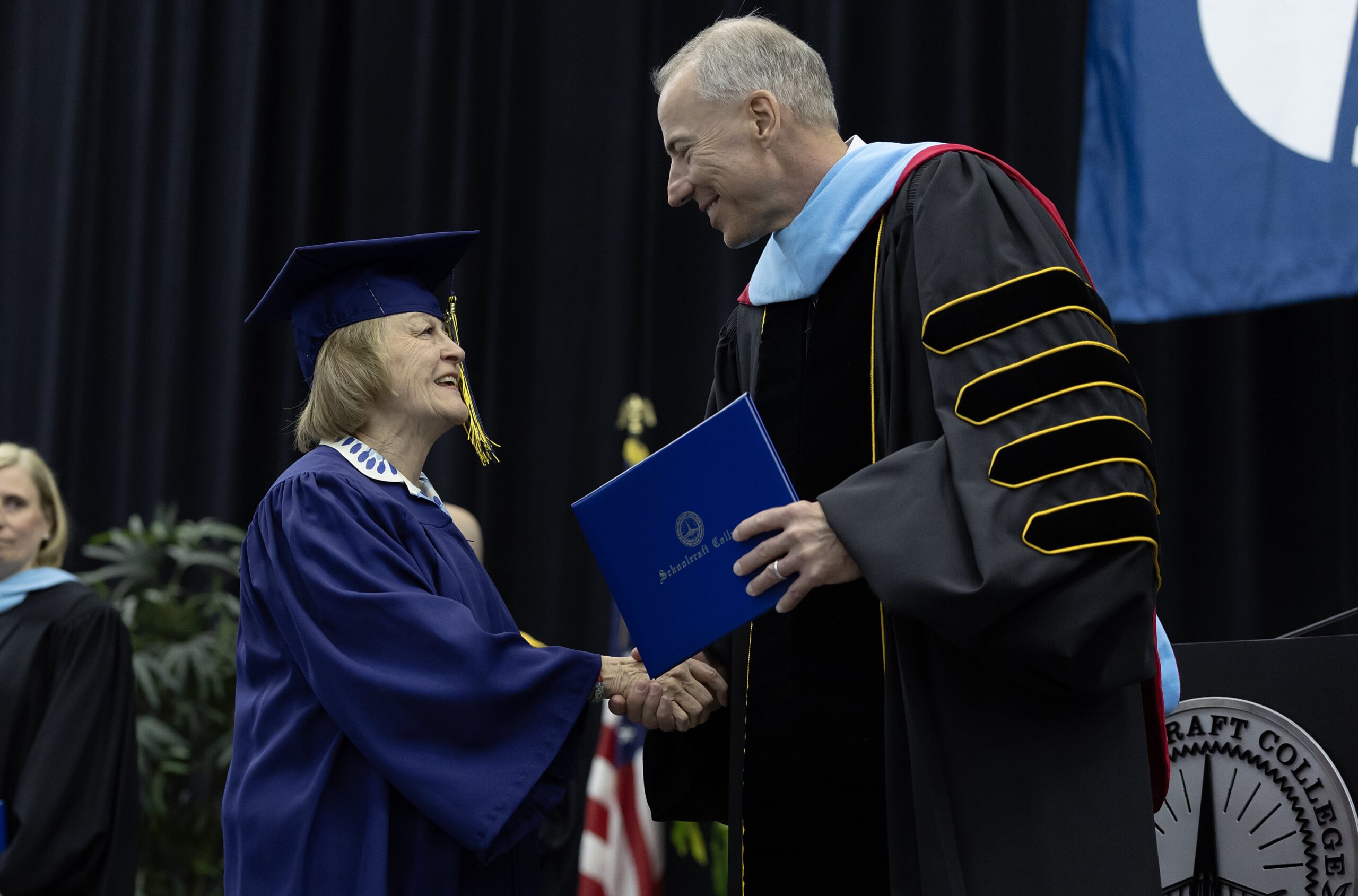student shaking hands with college president at graduation stage