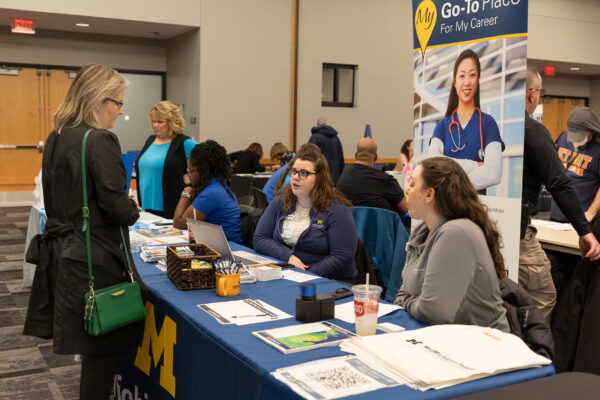 People talking at a University of Michigan table