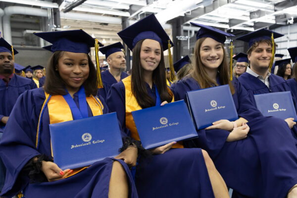 graduates in regalia holding their degrees