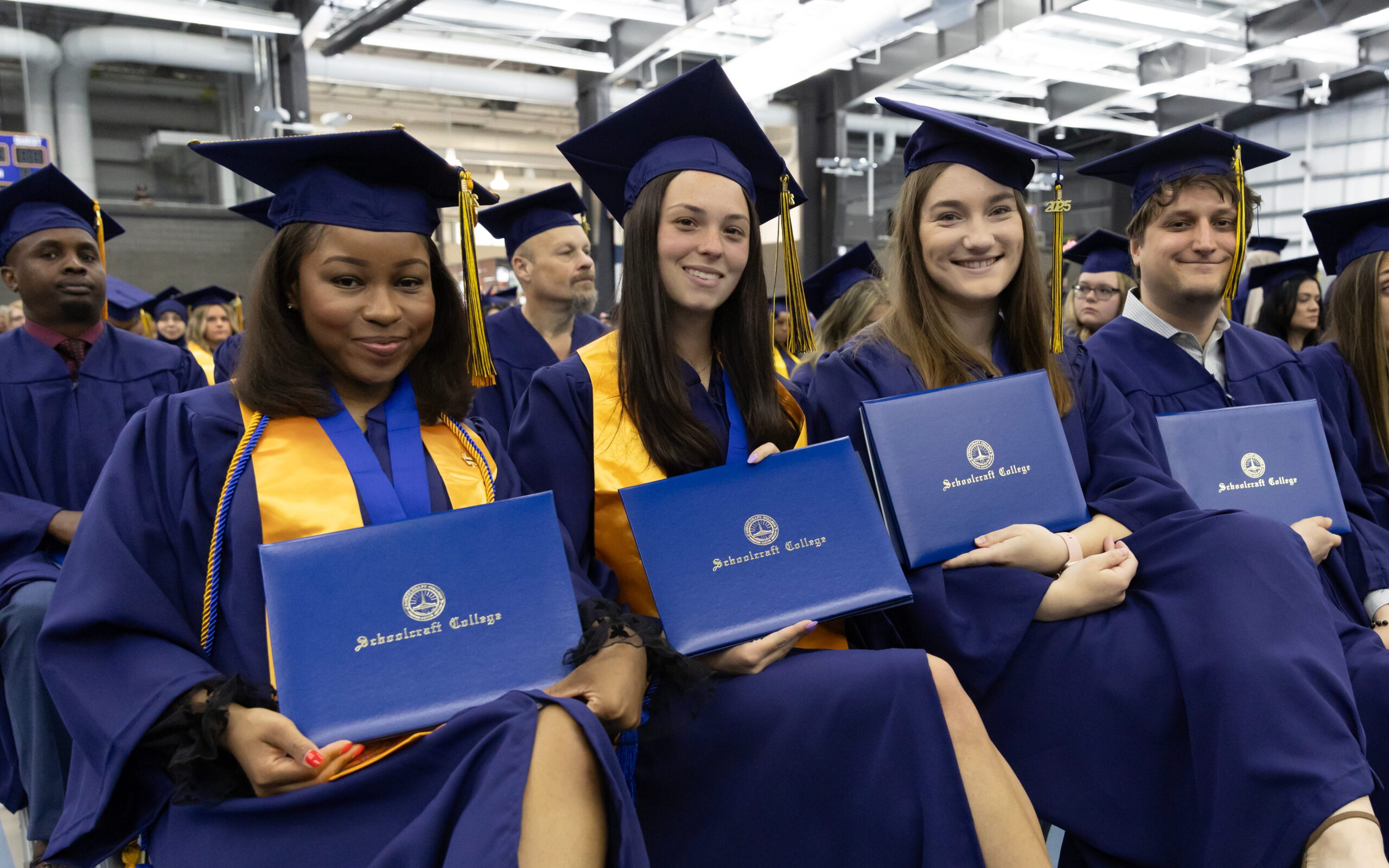 graduates in regalia holding their degrees