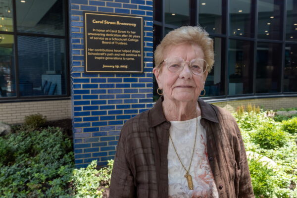 Carol Strom standing next to her building plaque